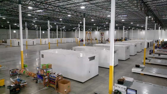 A large warehouse filled with several white e-houses arranged neatly throughout the space