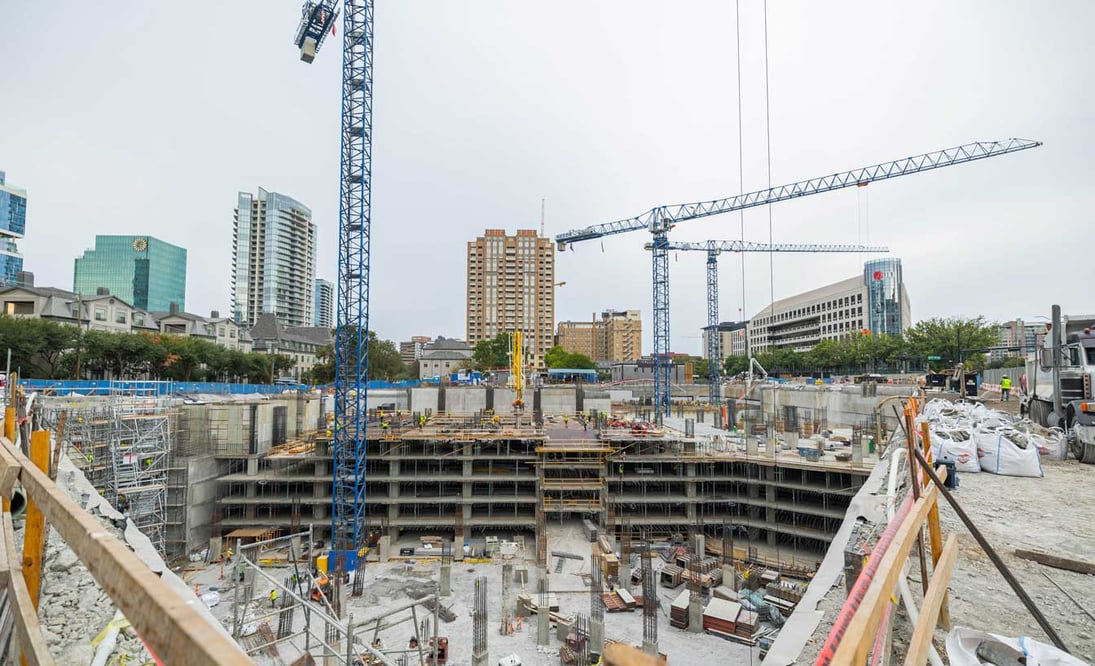 view of an active construction job site surrounded by high-rise buildings and cranes