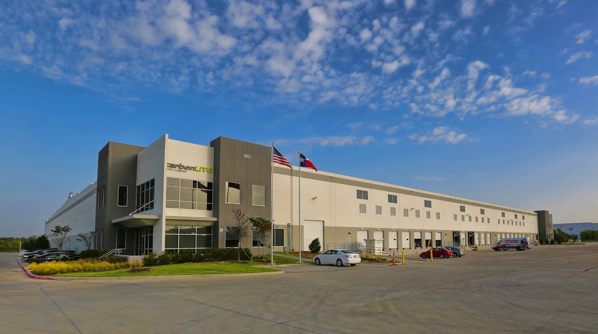 outdoor front view of a manufacturing facility with a few cars parked outside of the building