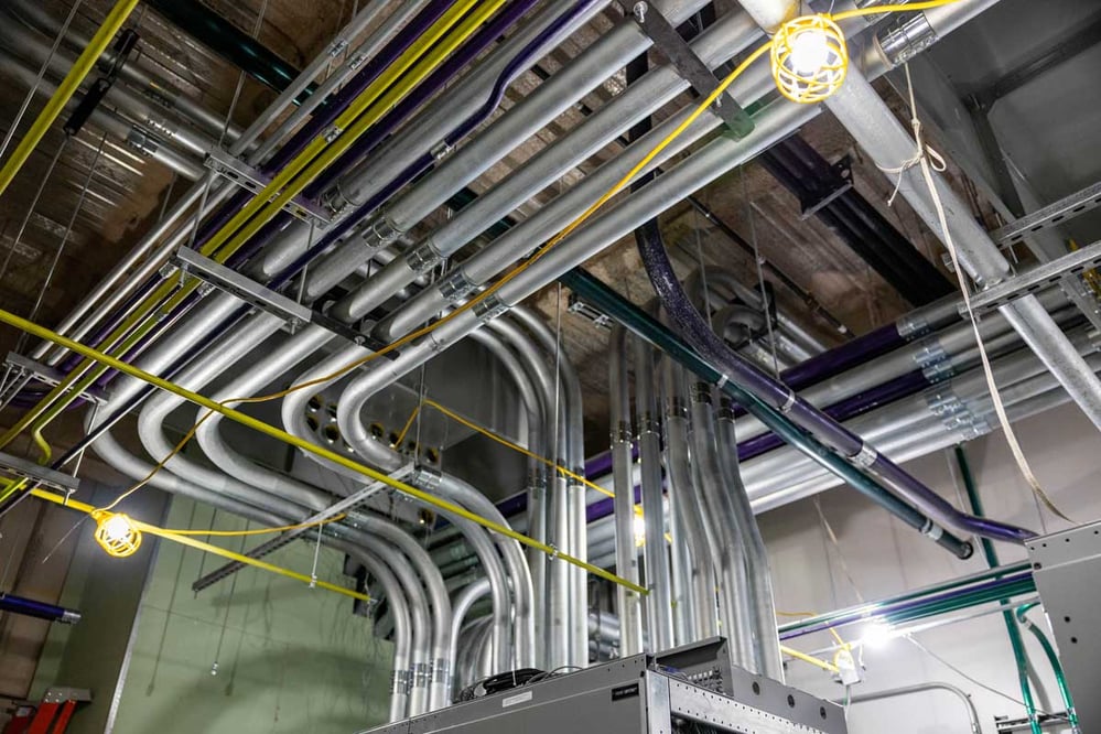 ceiling view of metal and colorful conduit routing into electrical equipment