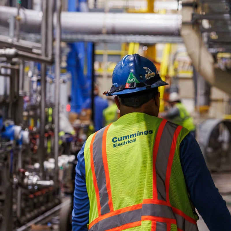 Cummings technician walking inside of an industrial manufacturing facility