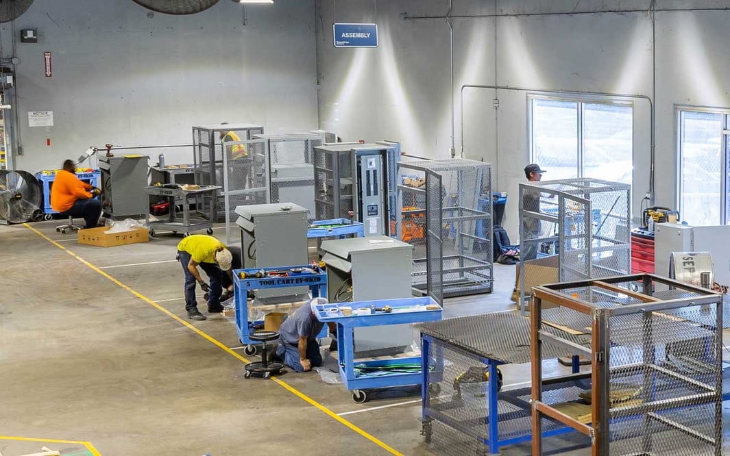Overhead view of multiple prefabricated electrical skids being produced in a manufacturing facility