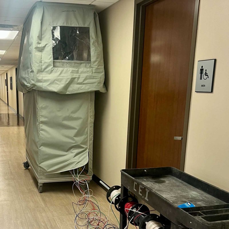 Worker repairing live electrical systems inside of a protective cover in a building hallway