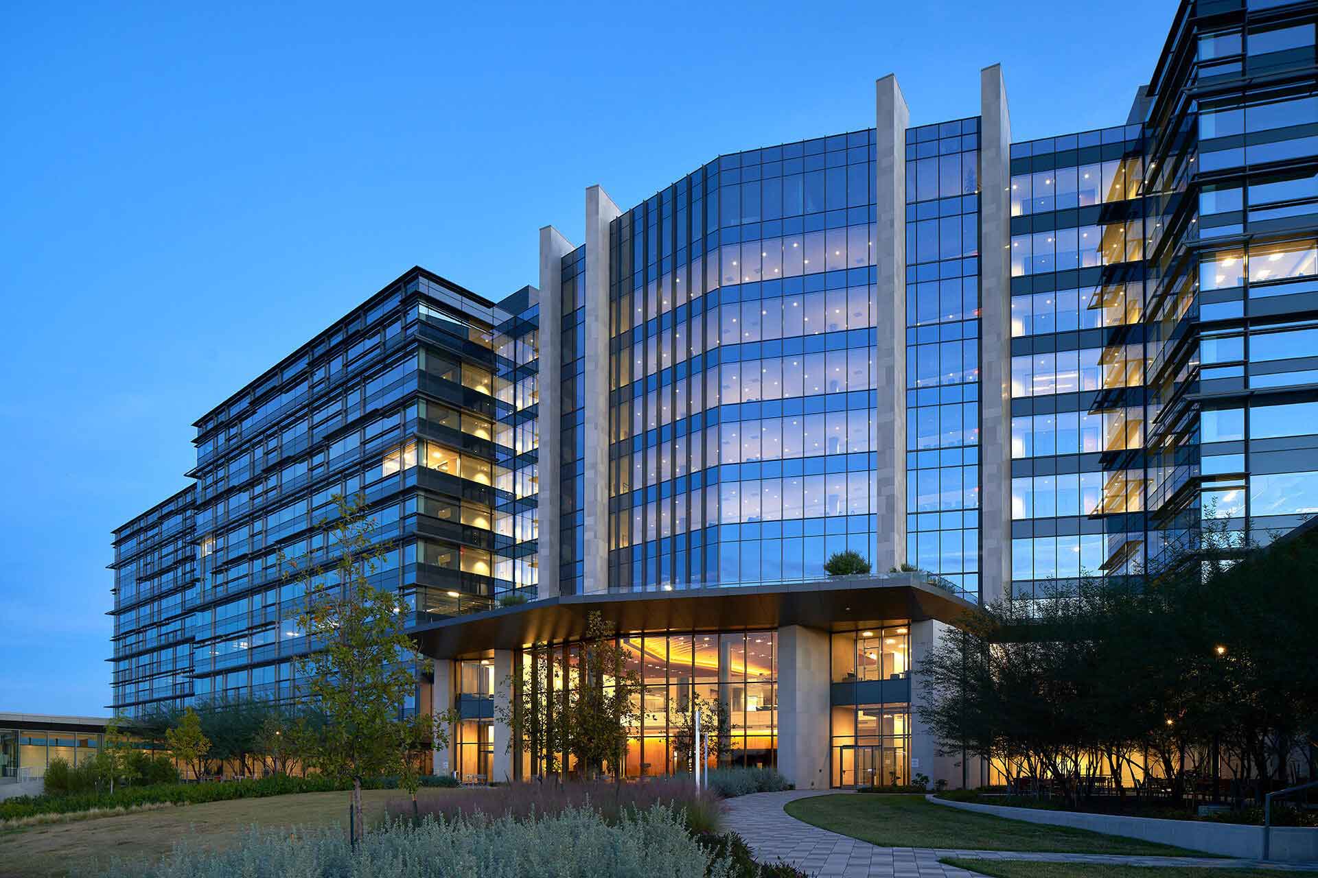 exterior view of a modern glass-paneled building with an illuminated front entrance