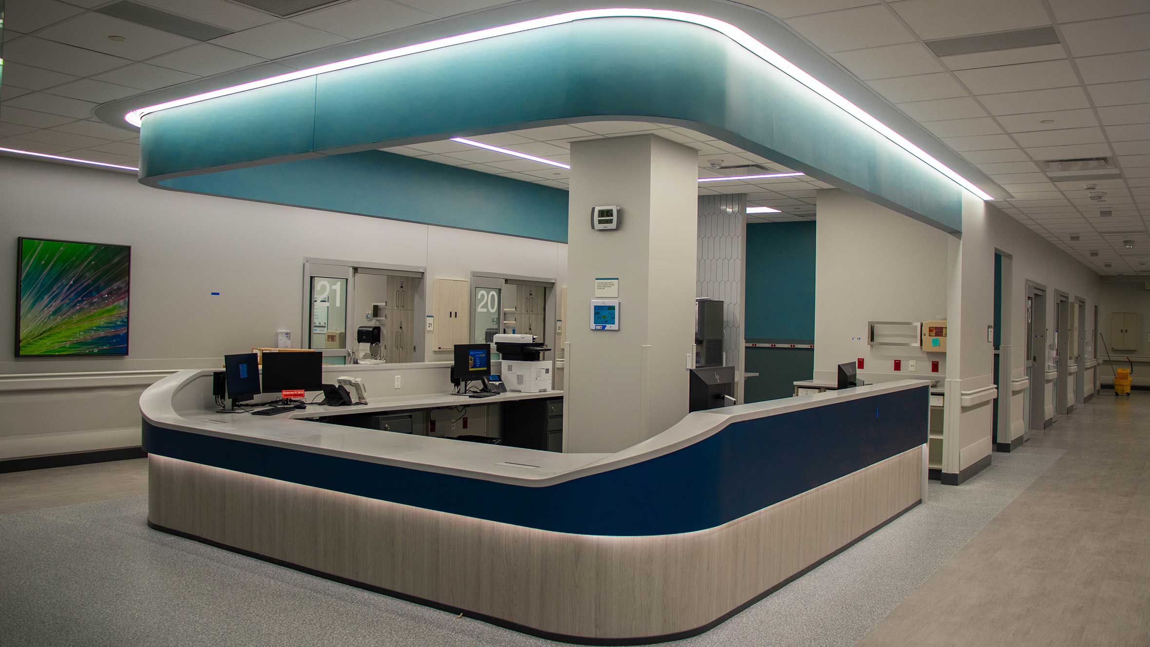 A hospital lobby featuring a reception desk with a computer, surrounded by seating areas and informational displays