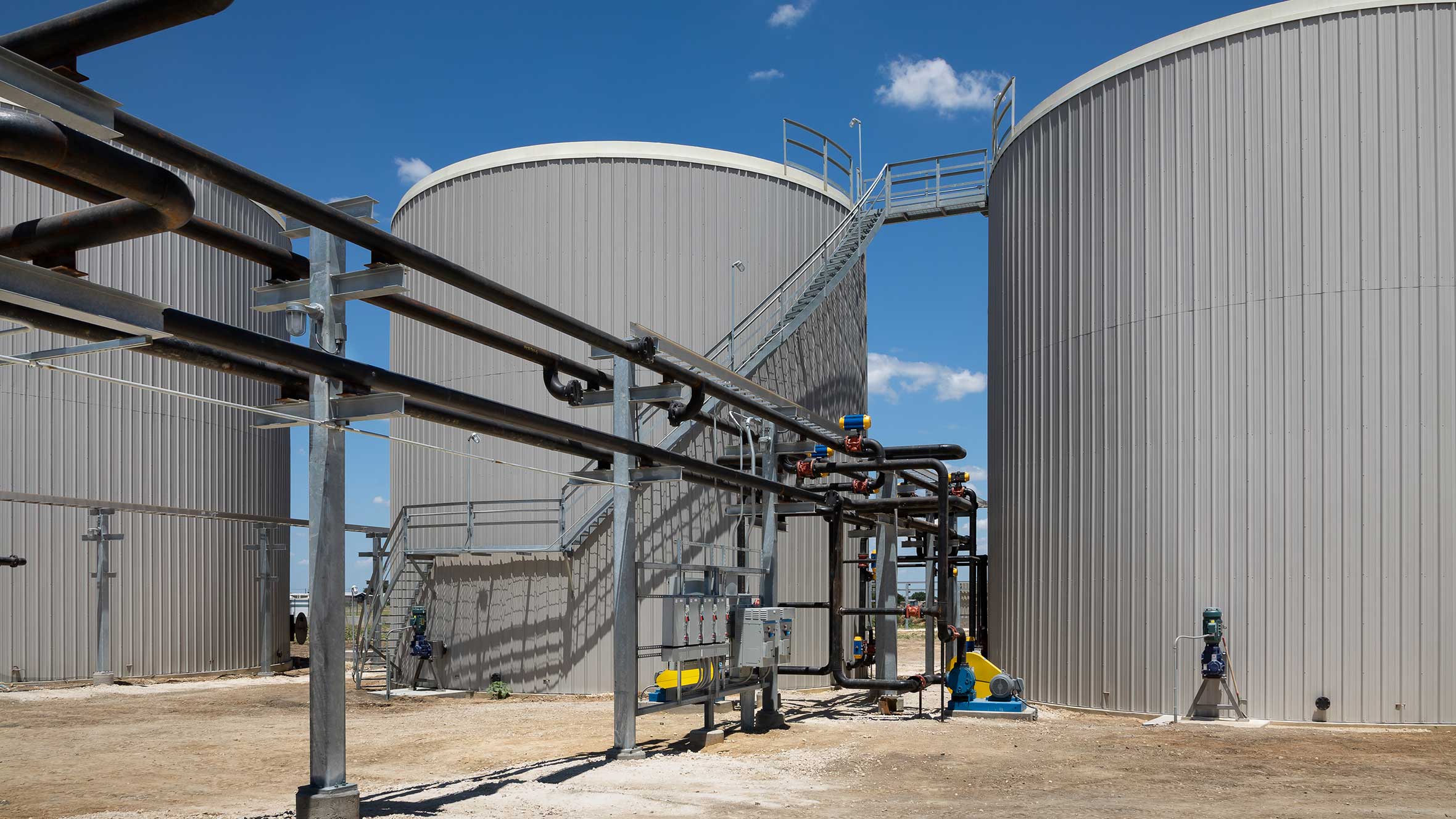 A large tank surrounded by various pipes, showcasing an industrial setup in the center of the image