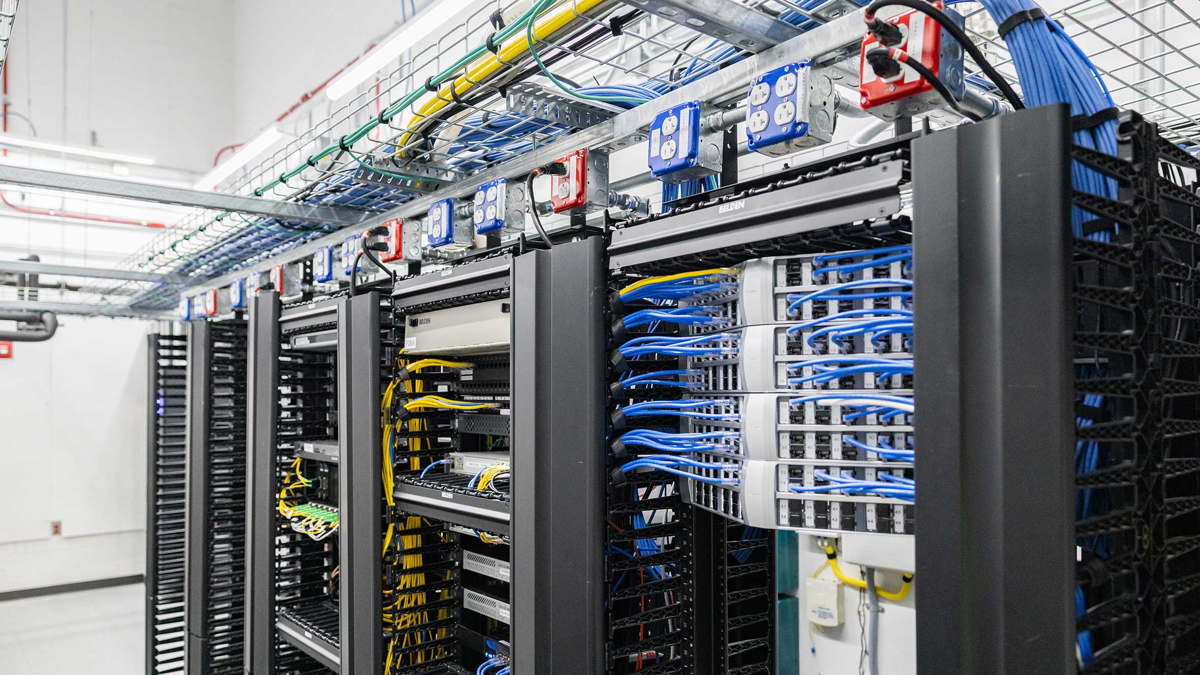 A spacious server room filled with numerous servers and tangled wires, showcasing a high-tech data center environment