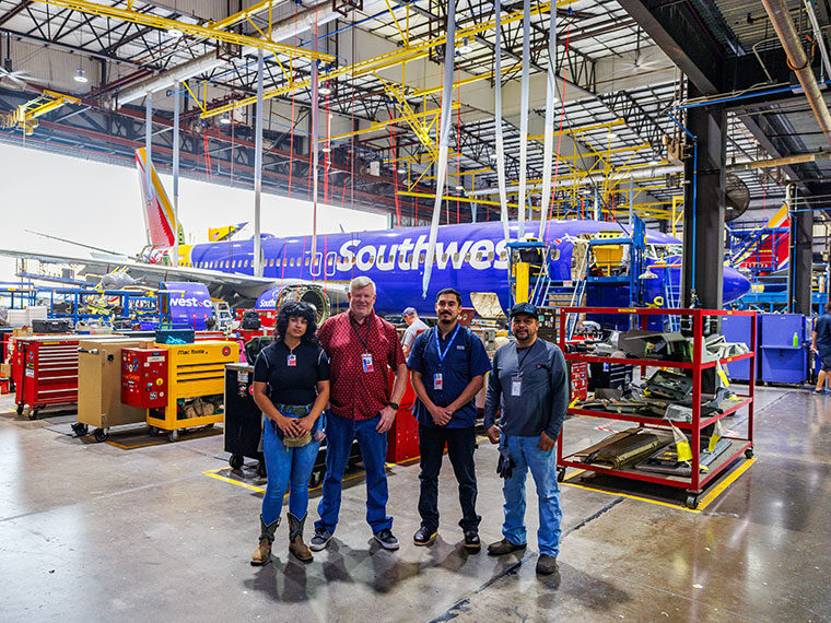 Group photo with people in front of an airplane in a Southwest airport hangar
