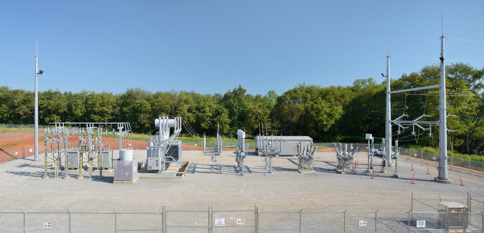 A newly constructed electrical substation with metal structures, transformers, and transmission lines