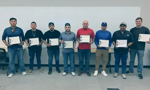 8 men standing in a line with awarded certificates