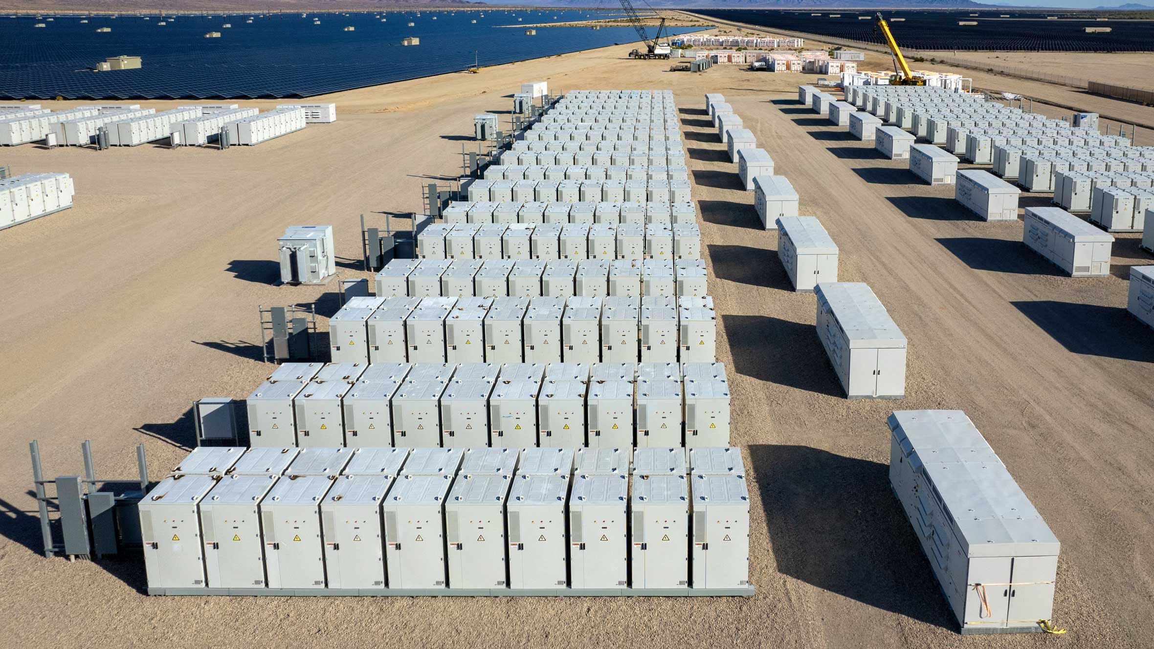 Aerial shot of a BESS yard with solar panels in the distance