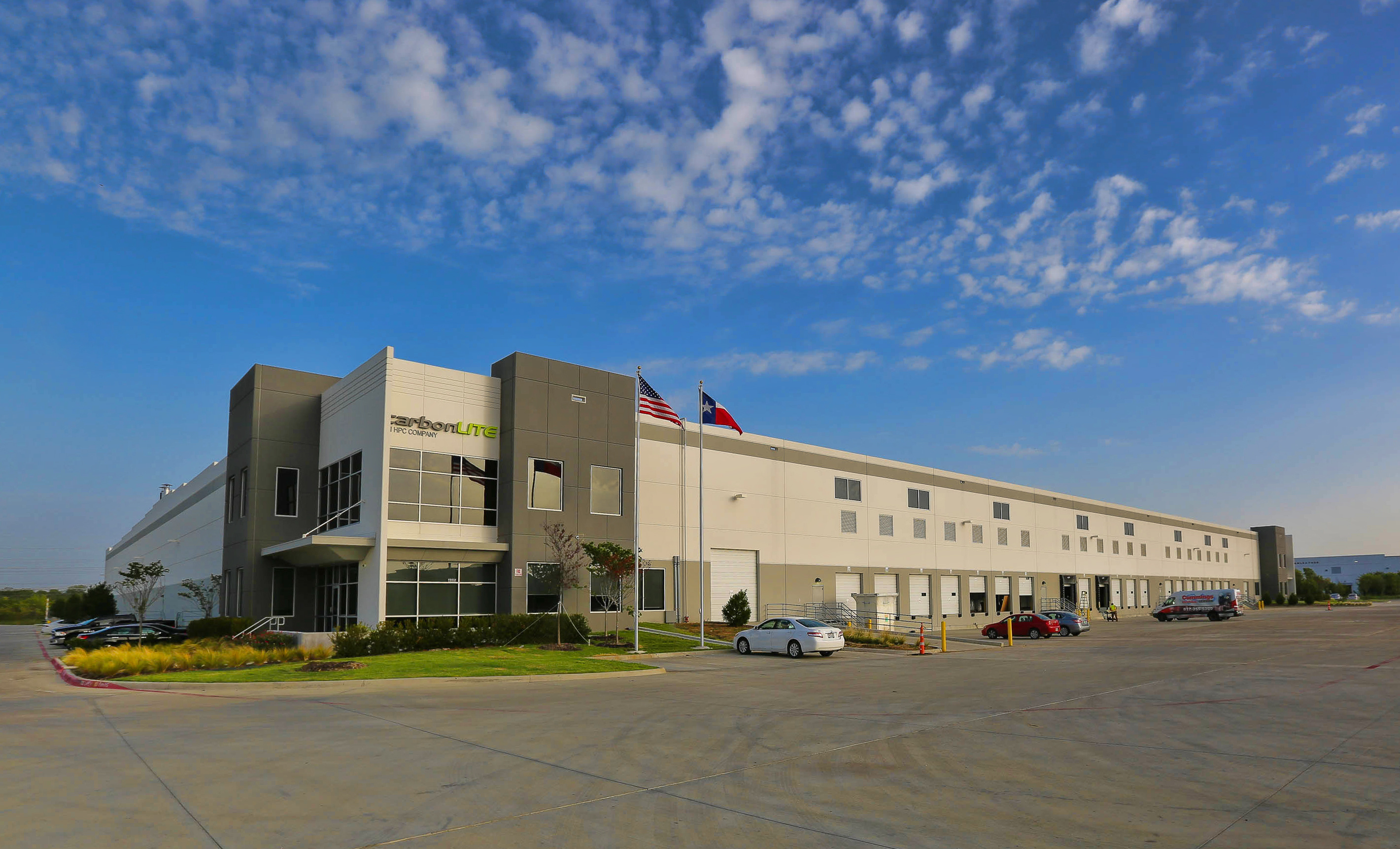 outdoor front view of a manufacturing facility with a few cars parked outside of the building