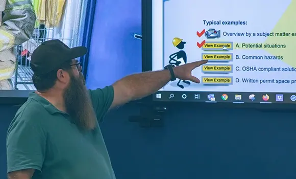 electrical trainer pointing at a screen with a powerpoint presentation displayed