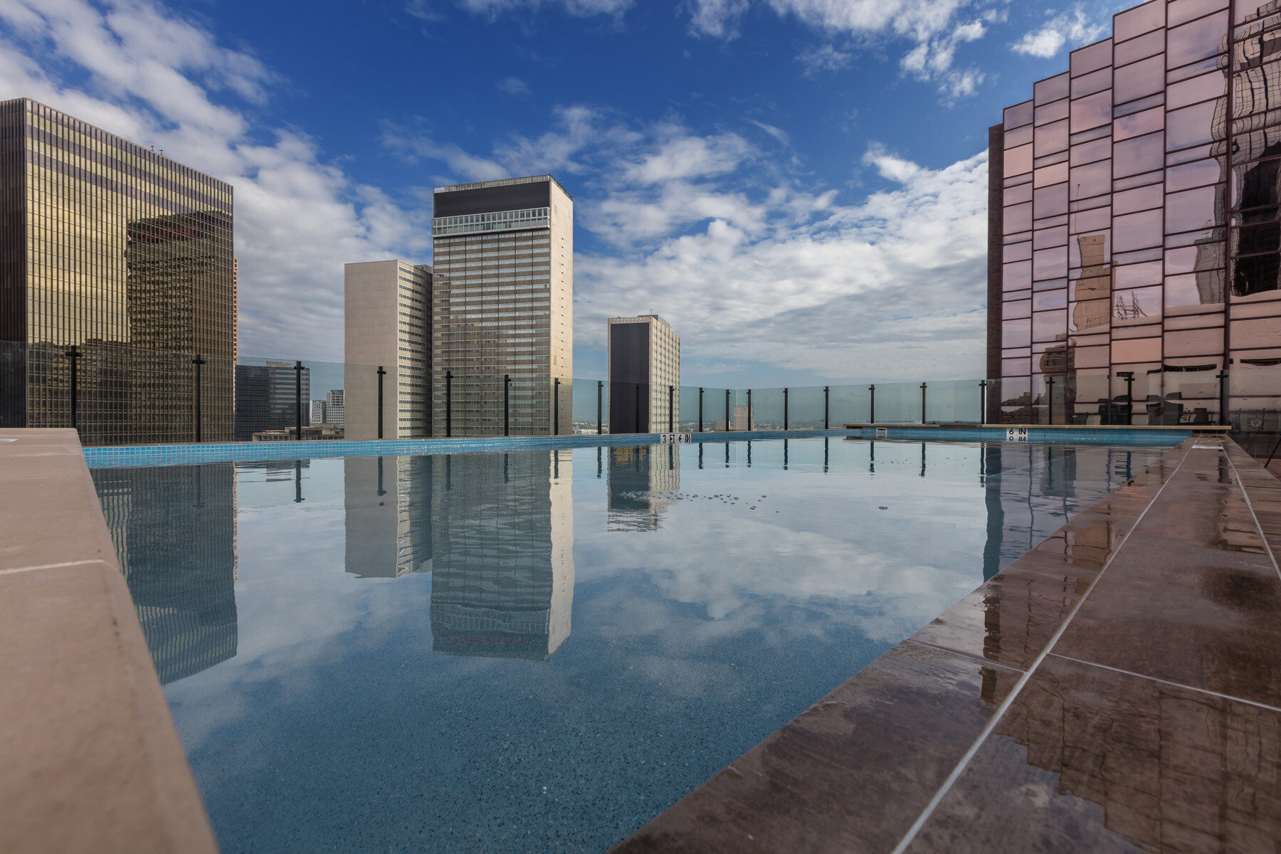 exterior view of a highly reflective pool on a downtown terrace overlooking multiple high-rise buildings