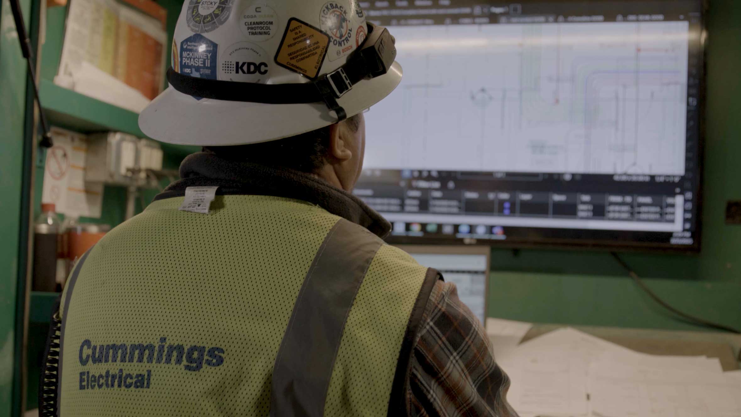 Cummings worker wearing protective equipment working on computer in a job site box close up