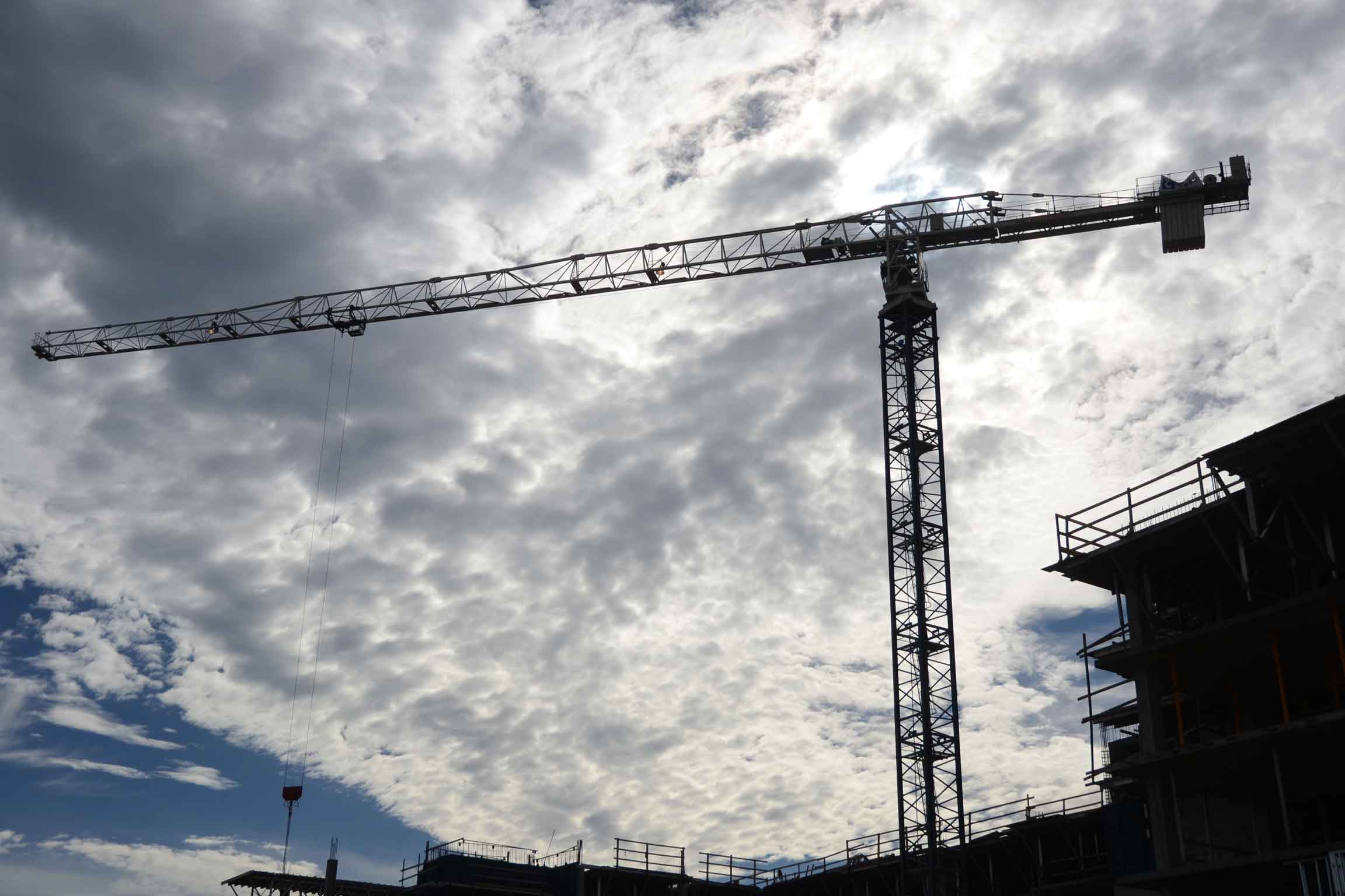 upwards view of a construction site with a large crane towering in the sky