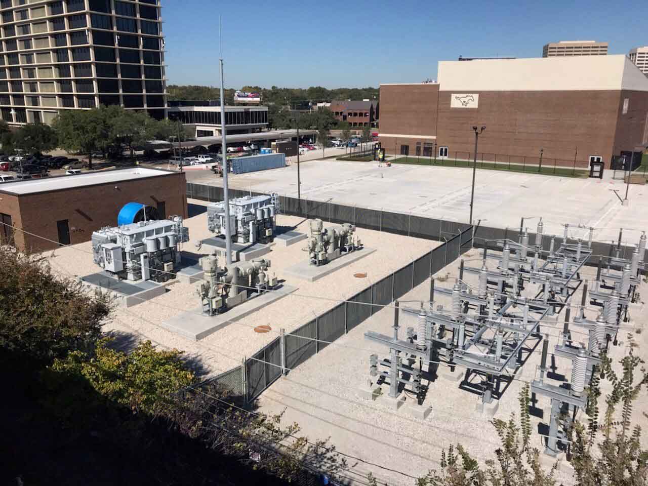 High-voltage substation located near a school campus surrounded by protective fencing