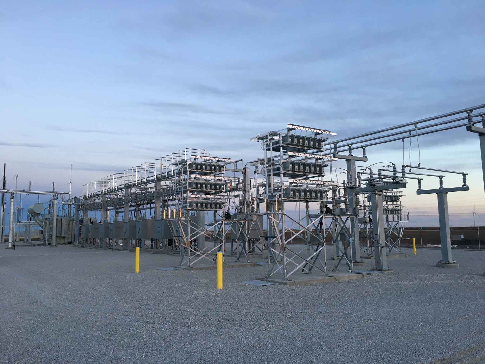 Wide-angle, sunset view of a large utility substation with multiple transformers and switchgear structures