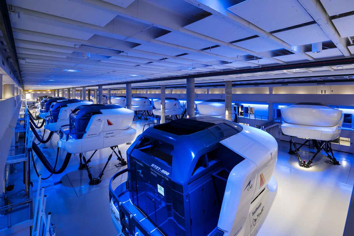 Dark indoor space with blue modern lighting surrounding rows of Southwest Airlines training machines