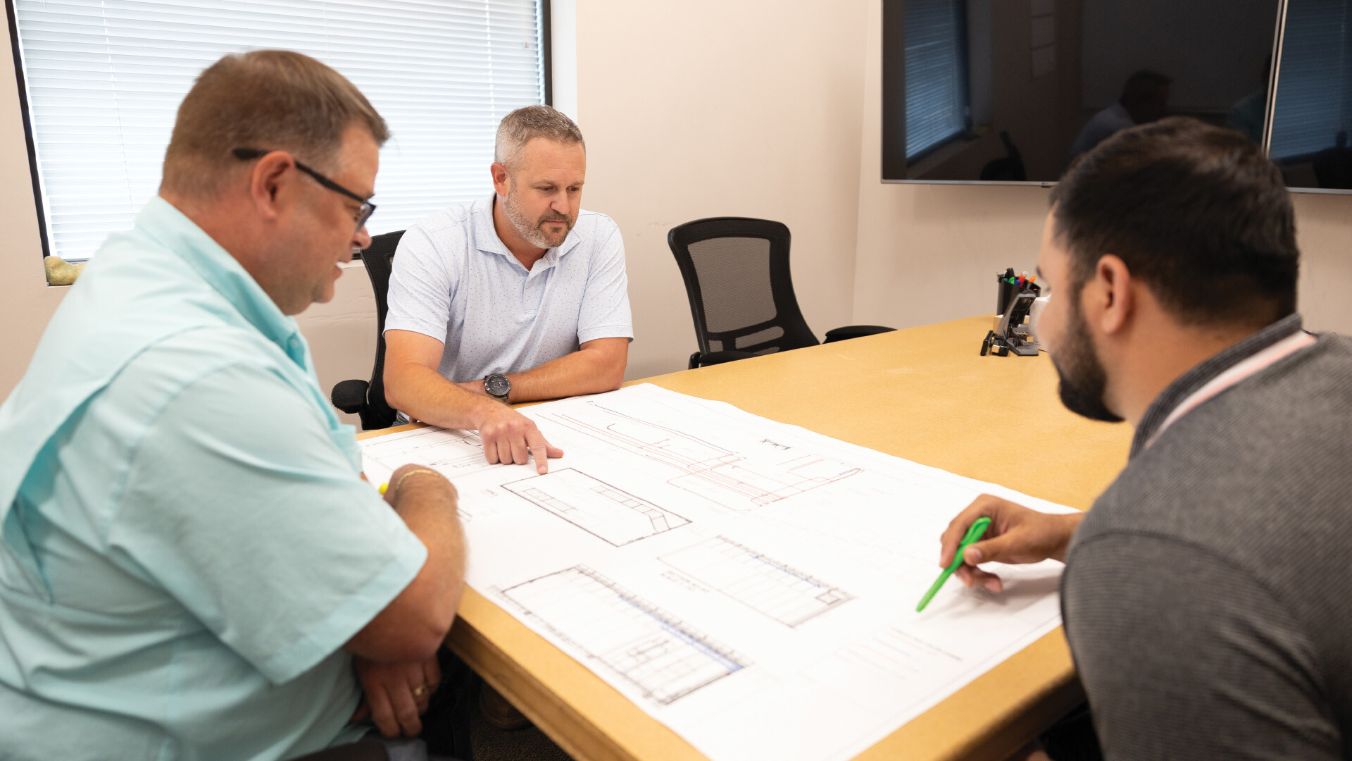 Men in room looking over manufacturing drawings