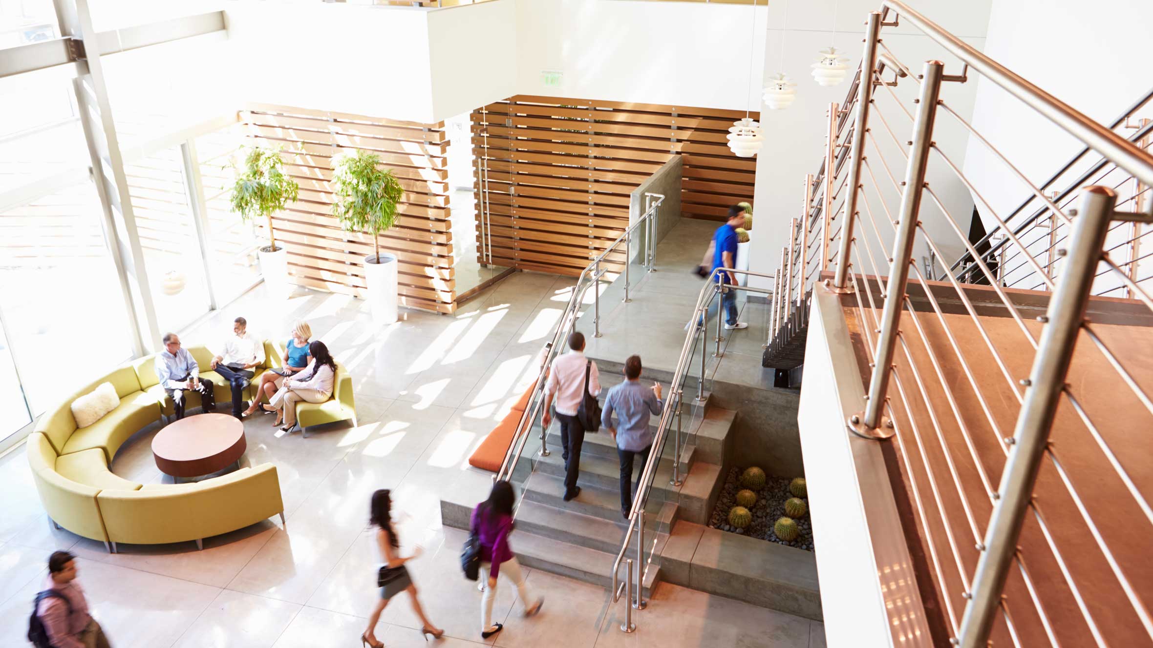 Office building lobby with workers sitting and moving up stairs