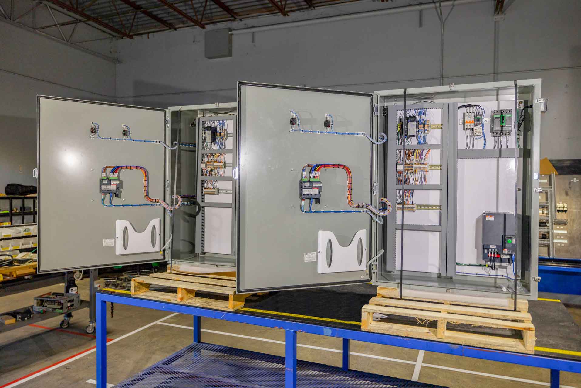 Custom-built electrical control panels staged on skids inside a prefabrication facility
