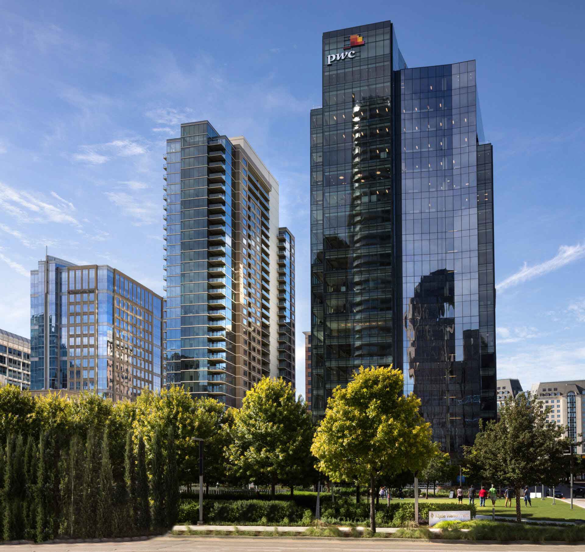 outdoor view of multiple high-rise buildings behind a green area with large trees