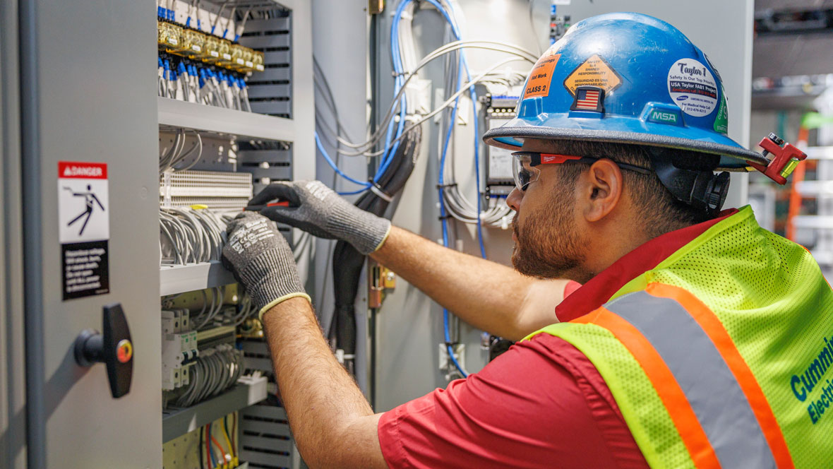 man with PPE working on an electrical control panel 