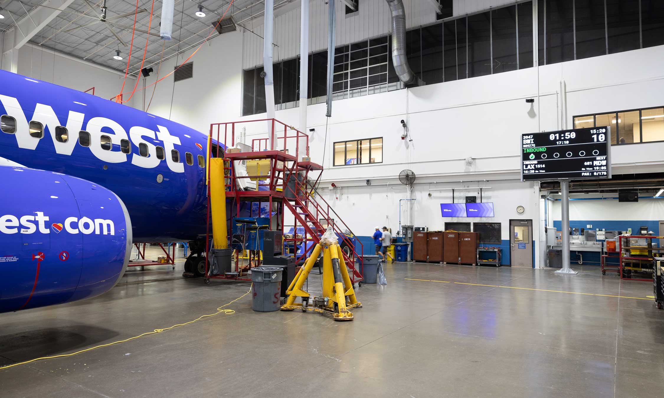 Technicians performing maintenance beside a Southwest airplane in a hangar