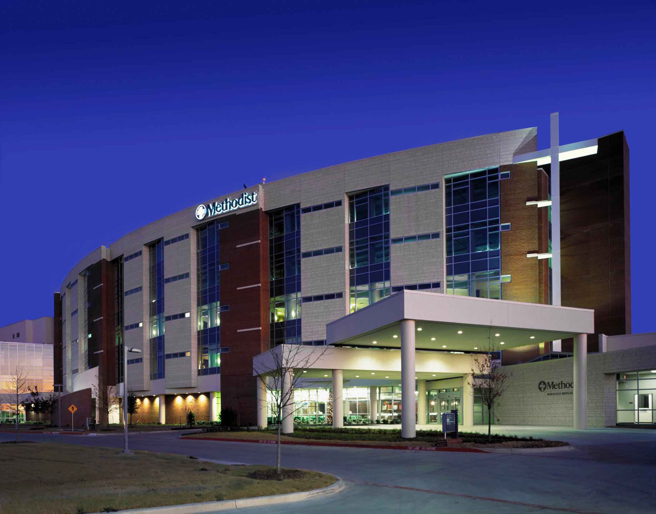 Exterior of Methodist Hospital at dusk, showing the main entrance and modern glass-and-brick facade.
