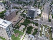overhead view of multiple tall buildings surrounding a green area and highway