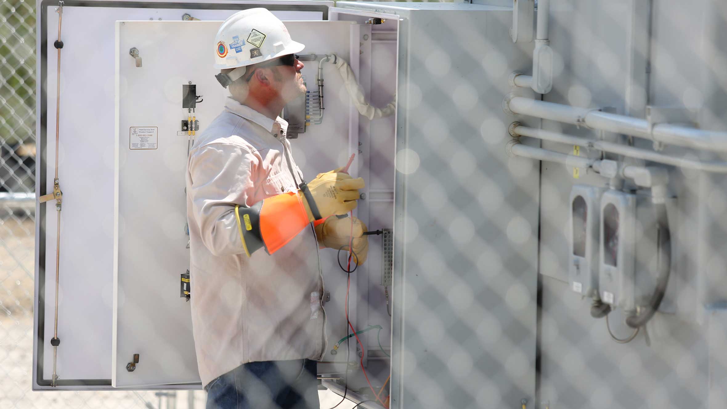 man with PPE analyzing a panel in a high voltage substation