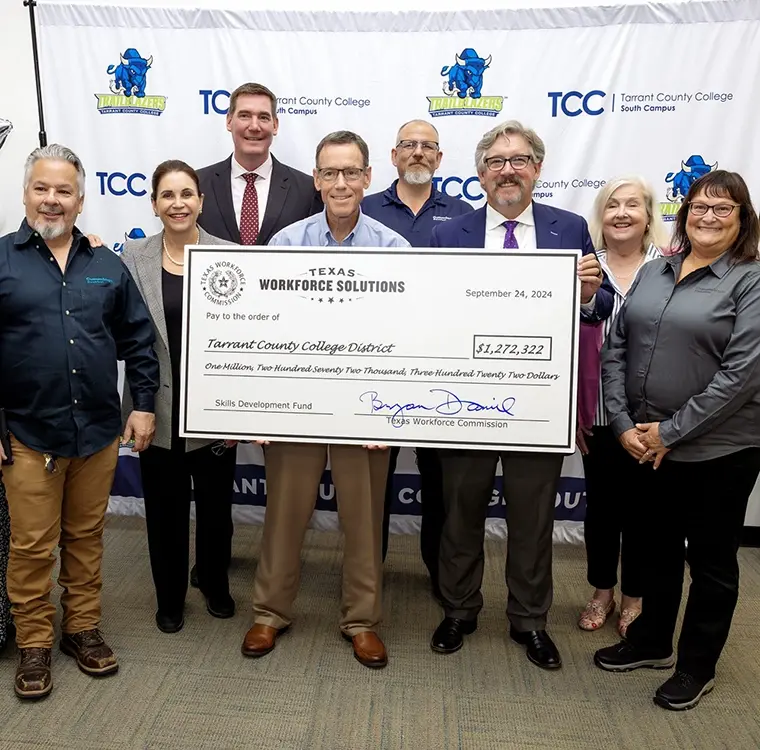 Professionals in business attire holding an awarded Texas Workforce Solutions check
